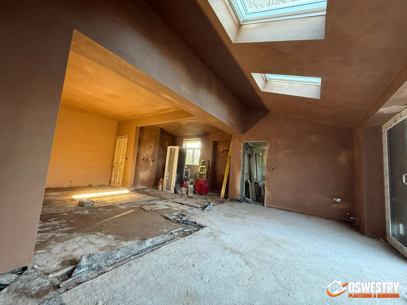 Open-plan UK extension freshly bonded and skimmed by Oswestry Plastering & Rendering — walls, ceilings, structural beams and skylight reveals all finished smooth in pink plaster